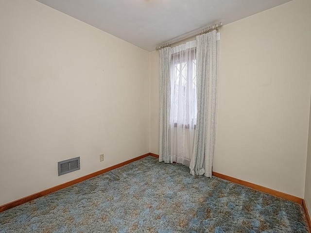 carpeted spare room with visible vents and baseboards