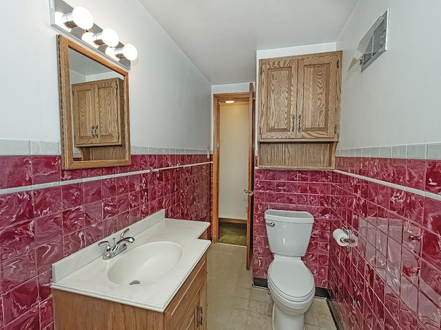 half bathroom with a wainscoted wall, toilet, vanity, and tile walls