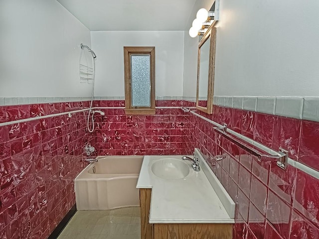 full bathroom with a wainscoted wall, vanity, tile walls, a bath, and tile patterned floors