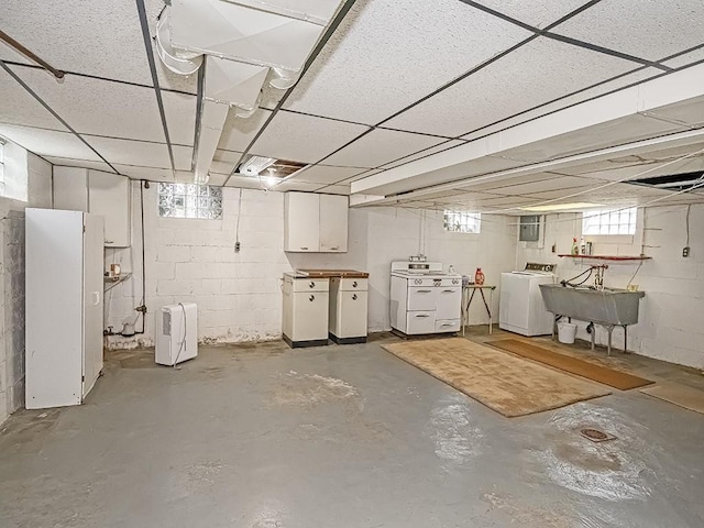 basement featuring a sink, separate washer and dryer, a drop ceiling, and freestanding refrigerator