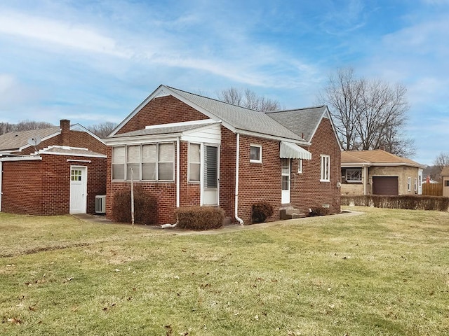 view of side of home featuring a garage, brick siding, a lawn, and entry steps