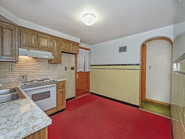 kitchen featuring white electric stove, light countertops, visible vents, wainscoting, and under cabinet range hood