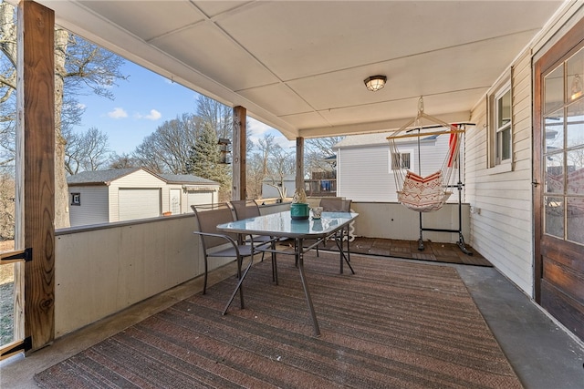 wooden deck featuring a detached garage and outdoor dining area