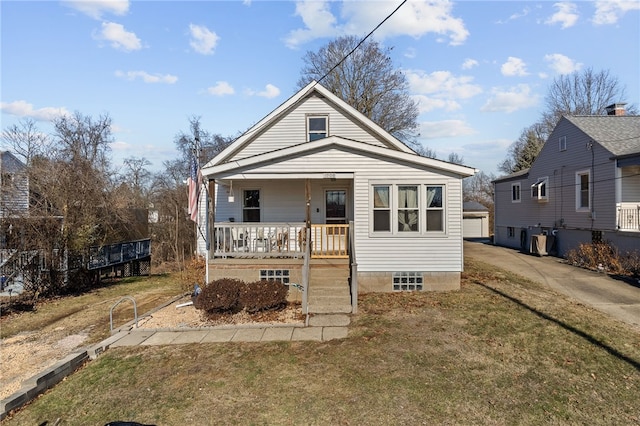 bungalow-style house with driveway, a garage, a porch, an outdoor structure, and a front lawn