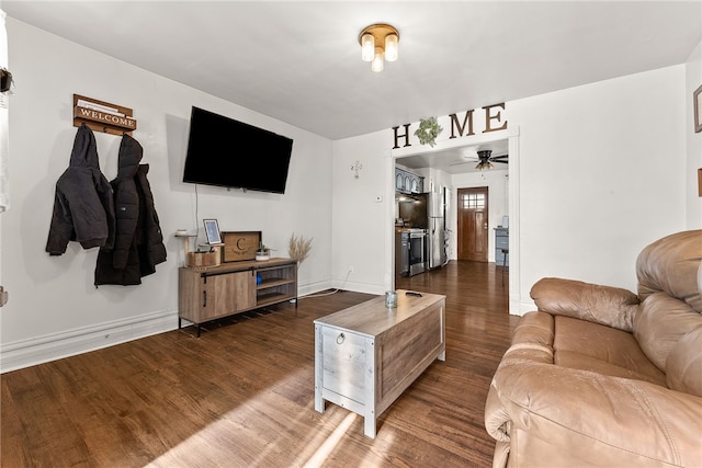 living area featuring ceiling fan, baseboards, and dark wood-style flooring