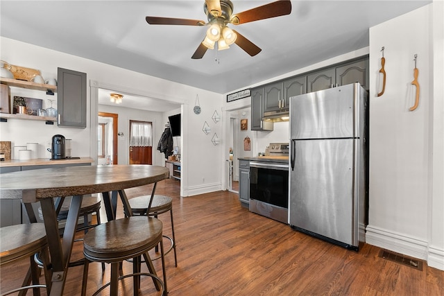 kitchen with baseboards, dark wood finished floors, stainless steel appliances, gray cabinetry, and under cabinet range hood