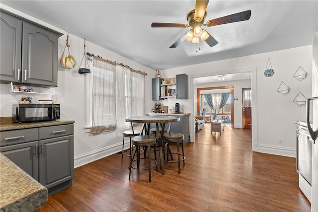 dining room with dark wood-style flooring, ceiling fan, and baseboards