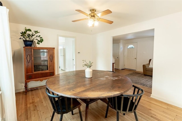 dining room featuring ceiling fan, light wood-style flooring, and baseboards