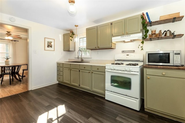 kitchen with dark wood finished floors, stainless steel microwave, a sink, under cabinet range hood, and white gas range oven