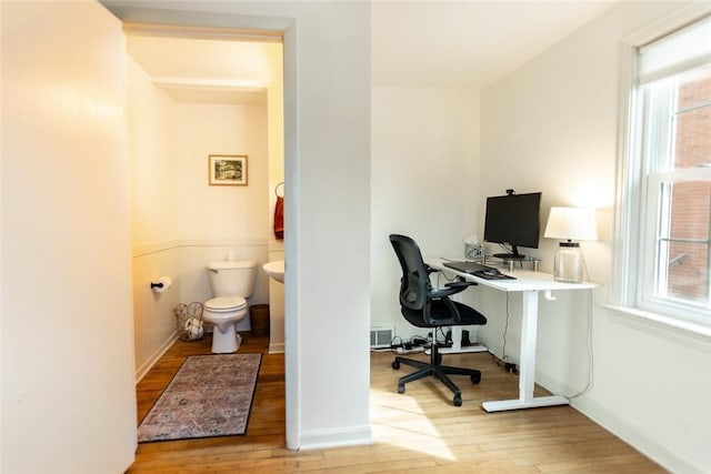 home office featuring wainscoting, plenty of natural light, visible vents, and wood finished floors