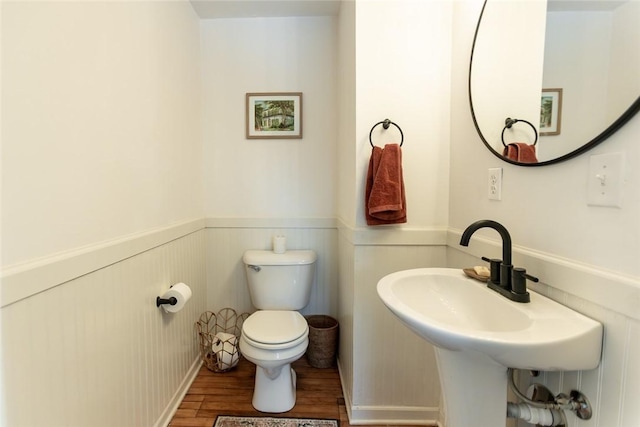 bathroom featuring wainscoting, a sink, toilet, and wood finished floors