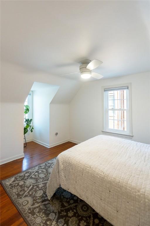 bedroom with a ceiling fan, vaulted ceiling, baseboards, and wood finished floors