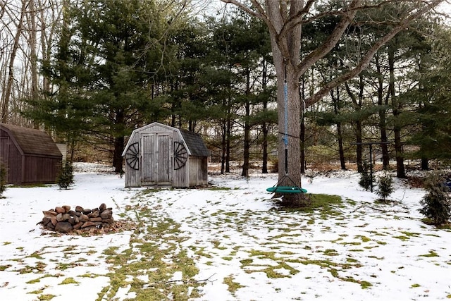 yard covered in snow with a storage unit and an outdoor structure