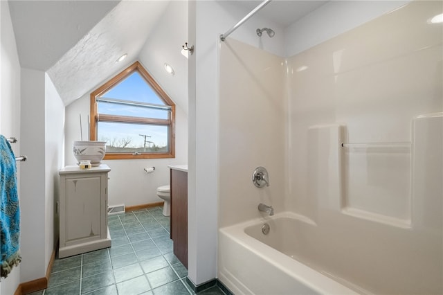 bathroom with toilet, tub / shower combination, vaulted ceiling, vanity, and tile patterned floors