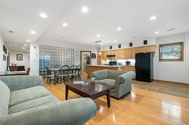 living room featuring baseboards, recessed lighting, and light wood-style floors