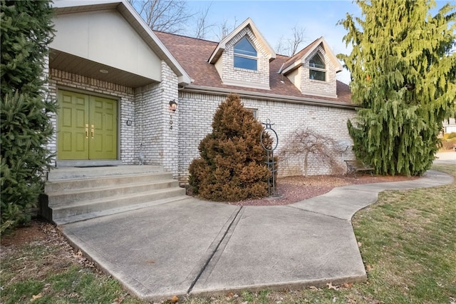 doorway to property with brick siding and roof with shingles