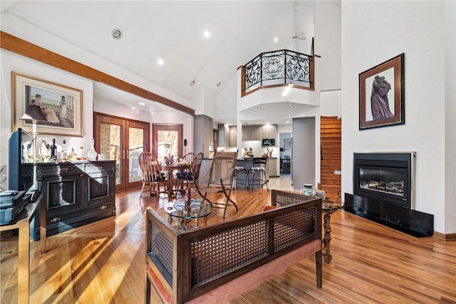 living room with recessed lighting, high vaulted ceiling, wood finished floors, and a glass covered fireplace