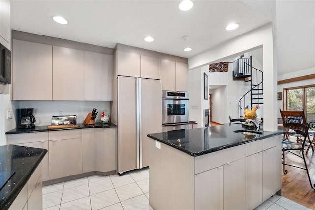 kitchen featuring recessed lighting, paneled refrigerator, and dark stone countertops