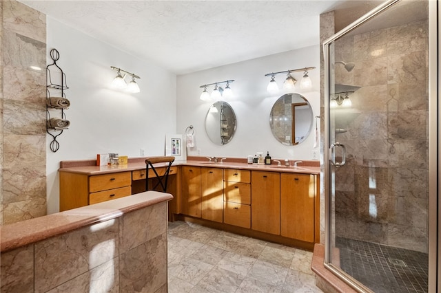 bathroom with a stall shower, a sink, a textured ceiling, and double vanity