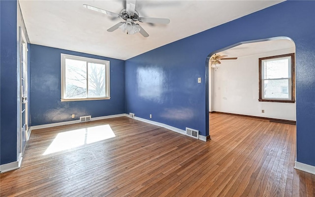 spare room featuring arched walkways, visible vents, ceiling fan, and hardwood / wood-style floors