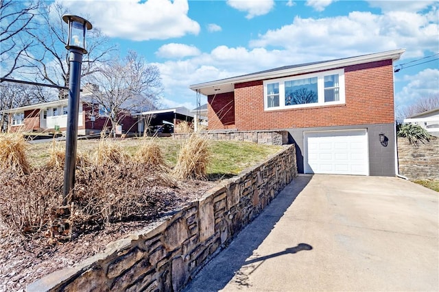 exterior space featuring driveway, an attached garage, and brick siding