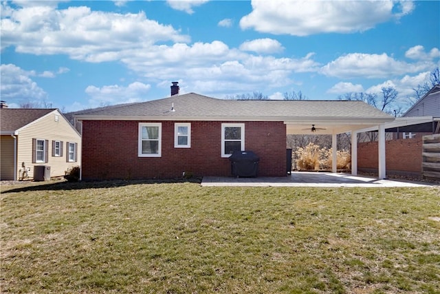 rear view of property with a patio, ceiling fan, cooling unit, a yard, and brick siding