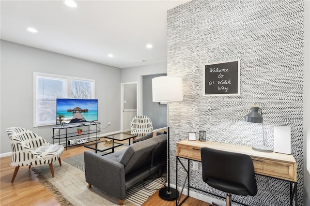 living area with an accent wall, wood finished floors, and recessed lighting