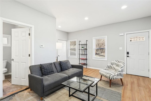 living area featuring baseboards, light wood finished floors, and recessed lighting