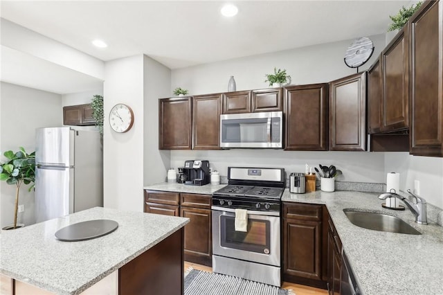 kitchen with recessed lighting, stainless steel appliances, a kitchen island, a sink, and dark brown cabinets