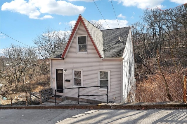 view of front of property featuring roof with shingles and fence