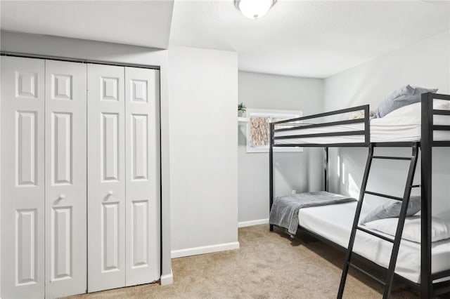 carpeted bedroom featuring a closet and baseboards