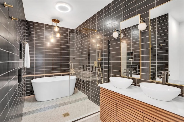 bathroom featuring double vanity, tiled shower, a sink, and tile walls