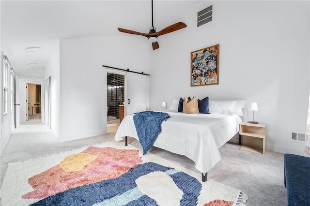 bedroom with a barn door, carpet, and visible vents