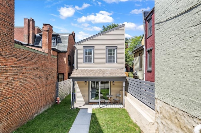 exterior space featuring a shingled roof, fence, a patio, and a yard