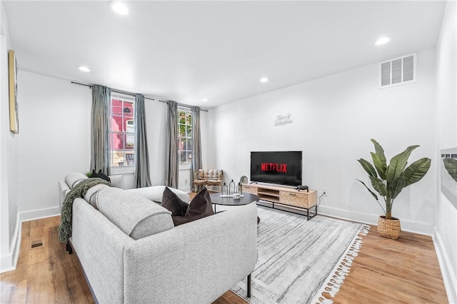 living room with recessed lighting, visible vents, baseboards, and wood finished floors