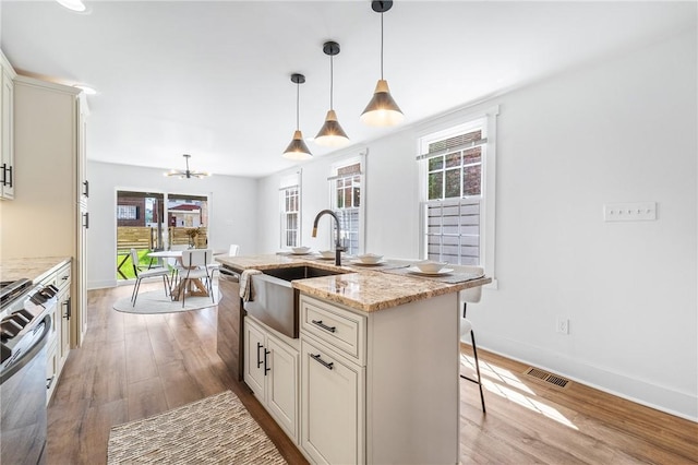 kitchen with light wood-style flooring, a sink, visible vents, range, and dishwasher