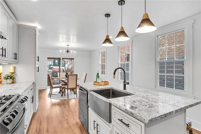 kitchen with dishwashing machine, decorative light fixtures, a sink, light wood finished floors, and gas range