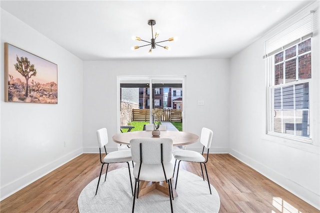 dining area with a notable chandelier, light wood-style flooring, and baseboards