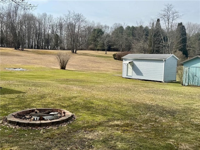 view of yard featuring an outbuilding, a fire pit, and a storage shed