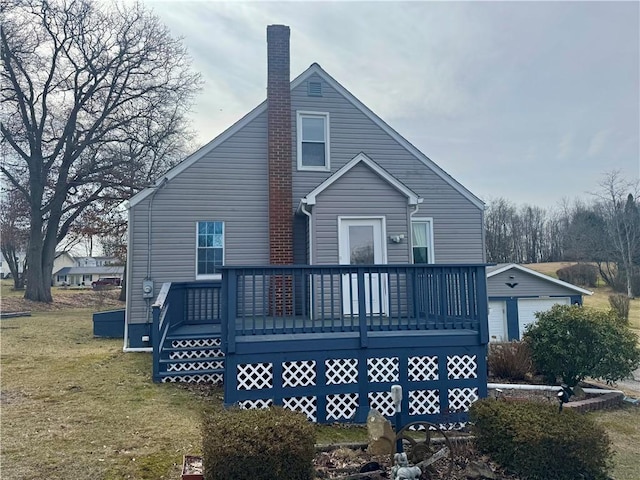 back of house with an outbuilding, a chimney, a wooden deck, and a lawn