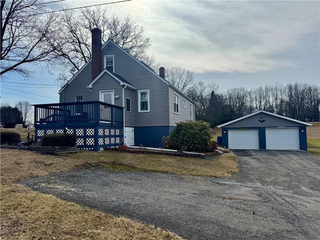 view of front of property featuring a garage, a chimney, an outdoor structure, and a wooden deck