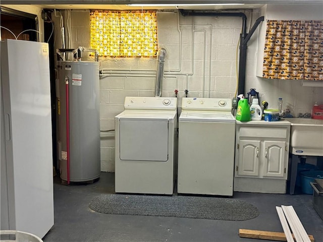 clothes washing area featuring concrete block wall, laundry area, water heater, separate washer and dryer, and a sink