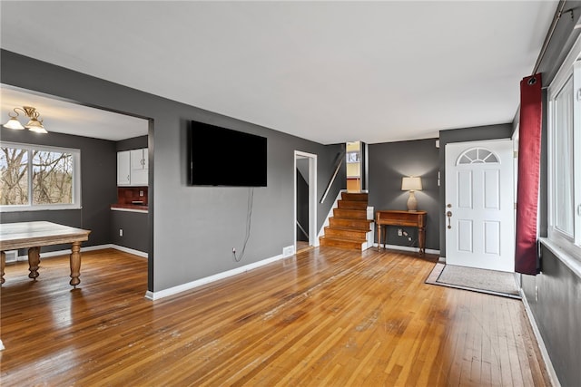 living room featuring stairway, light wood-style flooring, and baseboards