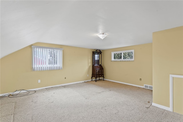 additional living space featuring carpet floors, lofted ceiling, visible vents, and baseboards