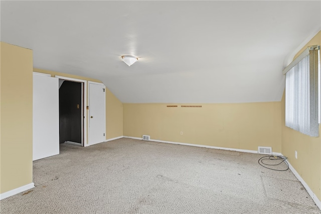 additional living space featuring vaulted ceiling, carpet flooring, visible vents, and baseboards