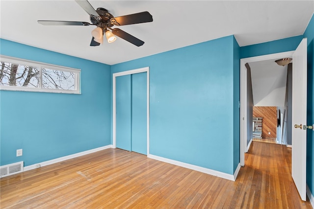 unfurnished bedroom with baseboards, a closet, visible vents, and wood finished floors