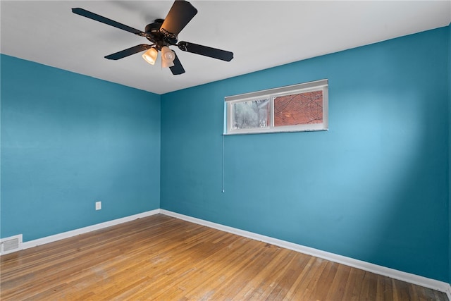 empty room with ceiling fan, hardwood / wood-style floors, visible vents, and baseboards