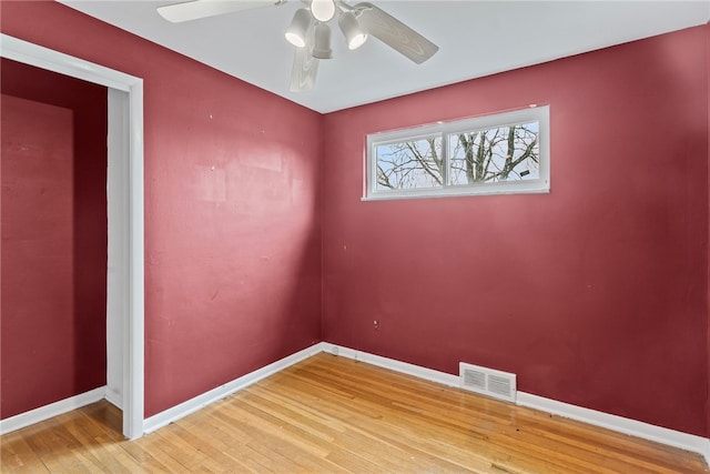 unfurnished room with a ceiling fan, light wood-type flooring, visible vents, and baseboards