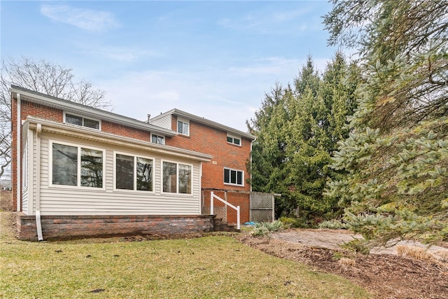 rear view of house featuring brick siding and a lawn