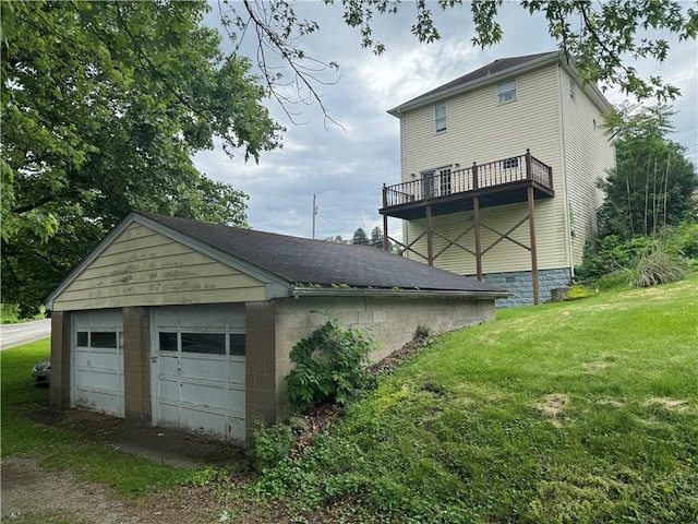 rear view of house with a detached garage, concrete block siding, and a yard